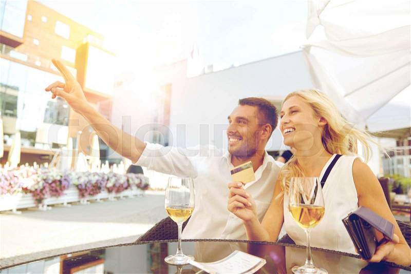 Date, people, payment and finances concept - happy couple with wallet, credit card and wine glasses calling waiter for bill payment at restaurant, stock photo
