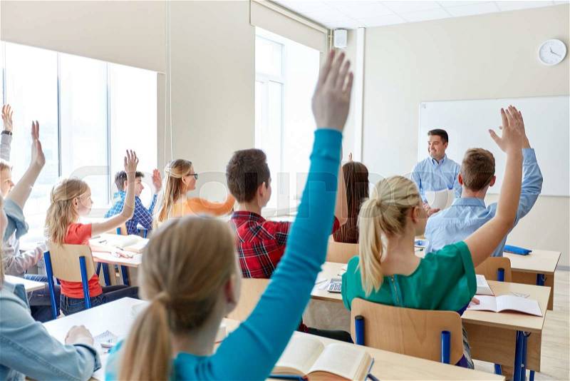 Education, high school, teaching, learning and people concept - group of happy students raising hands and teacher in classroom, stock photo