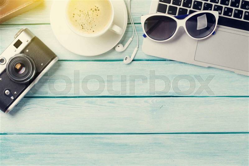 Desk with laptop, coffee and camera on wooden table. Workplace. Top view with copy space. Sunny toned, stock photo