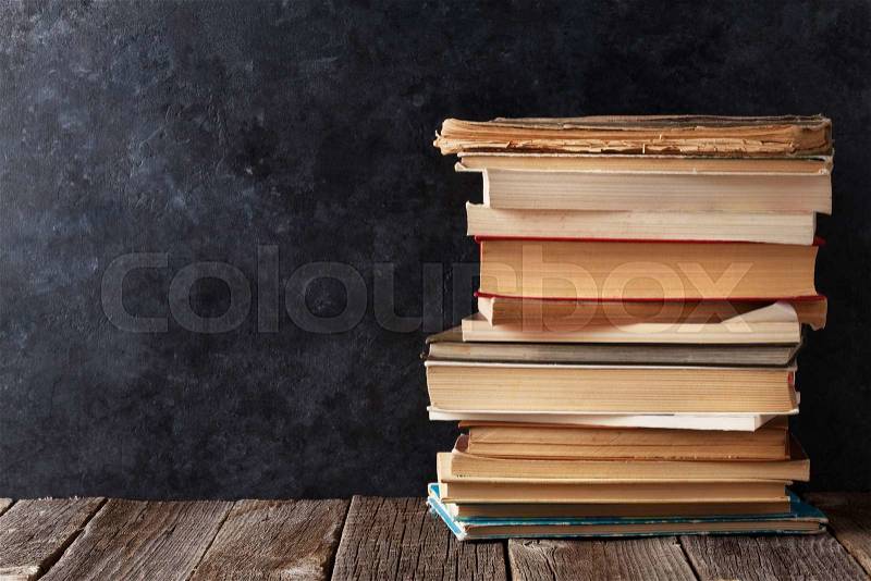 Old books in front of classroom chalk board. Back to school concept with copy space, stock photo