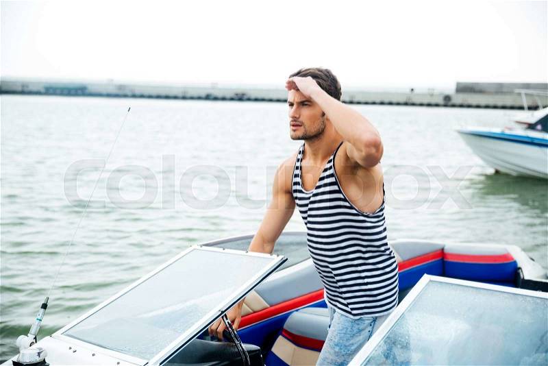Young handsome man preparing boat to start a journey, standing on the boat, stock photo