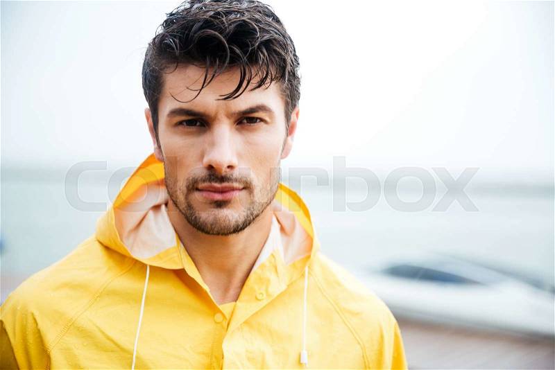 Close up portrait of a handsome young sailor man in yellow cloak, stock photo