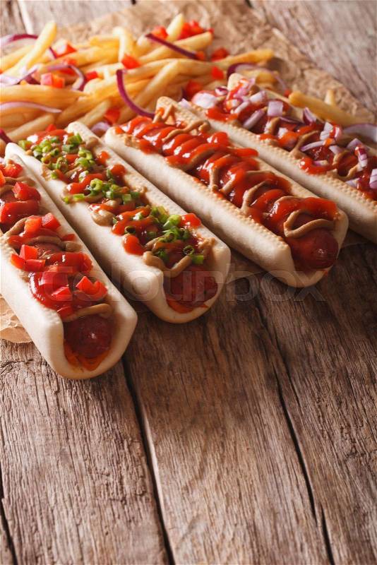 Traditional fast food: hot dogs and french fries on a paper on the table. vertical, rustic style\, stock photo