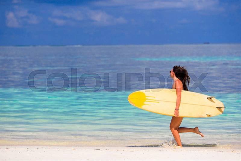 Happy young surf woman at the beach with a surfboard, stock photo