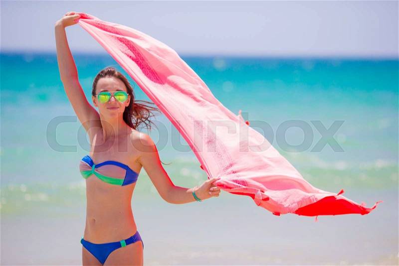 Young woman with beach towel during tropical vacation. Beautiful girl enjoy her summer holidays, stock photo