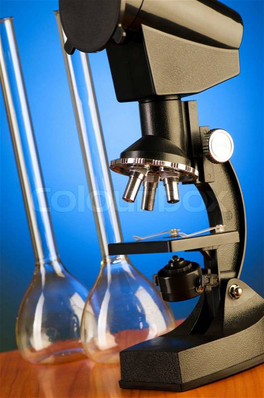 Microscope against blue gradient background, stock photo