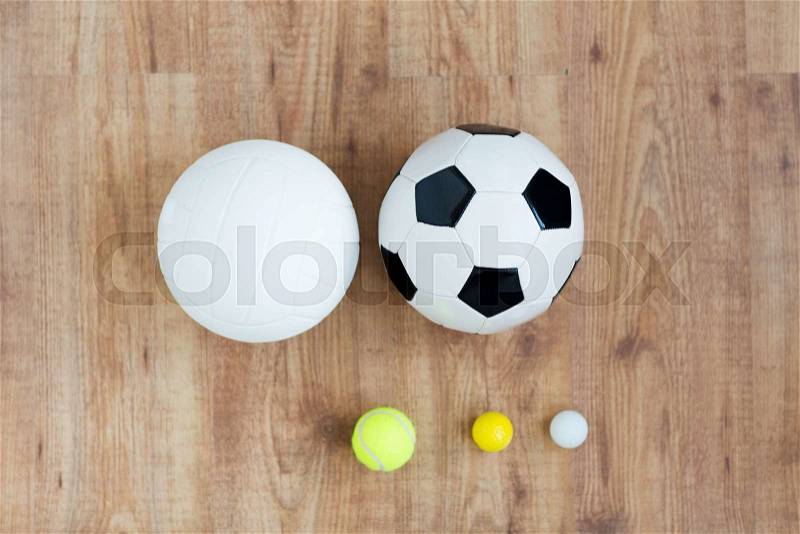 Sport, fitness, game, sports equipment and objects concept - close up of different sports balls set on wooden floor from top, stock photo