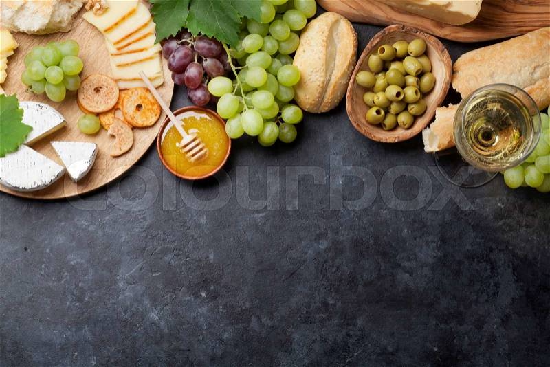 White wine, grape, bread, cheese plate and honey over stone table. Top view with copy space, stock photo