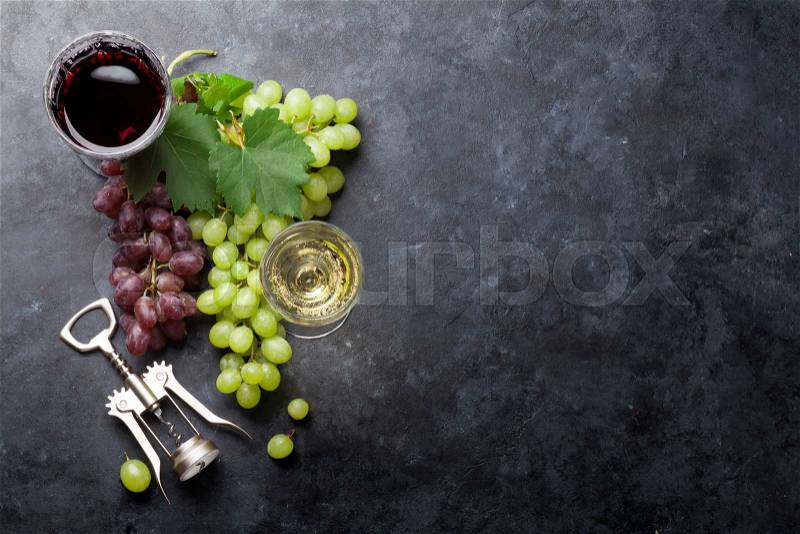 Red and white wine glasses and grape over stone table. Top view with copy space, stock photo