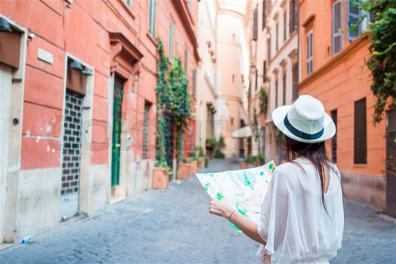 Happy young woman with a city map on desert street in Europe. Travel tourist woman with map in Rome outdoors during holidays in Italy, stock photo