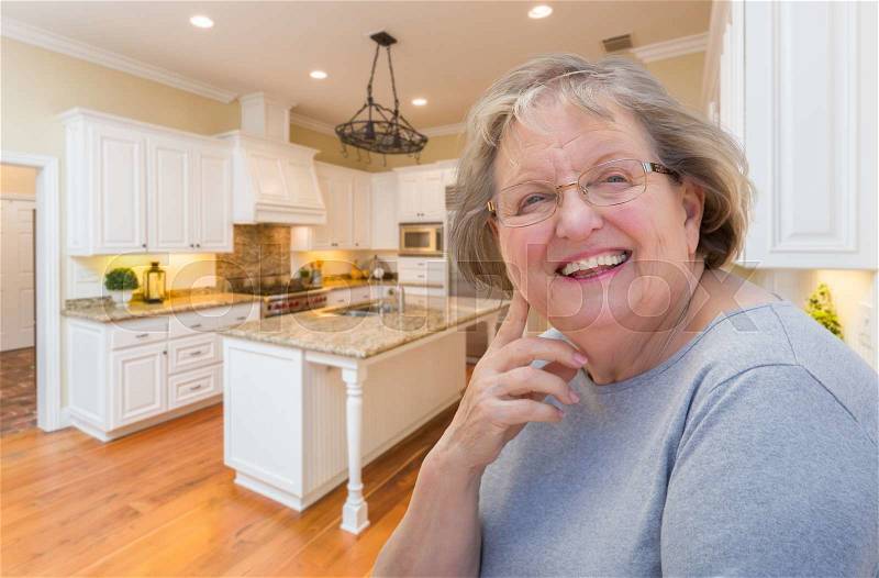 Happy Senior Woman Sitting In Custom Kitchen Interior, stock photo