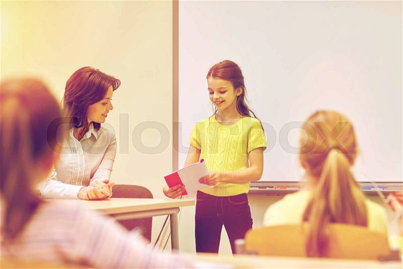 Education, elementary school, learning and people concept - group of school kids with teacher in classroom, stock photo