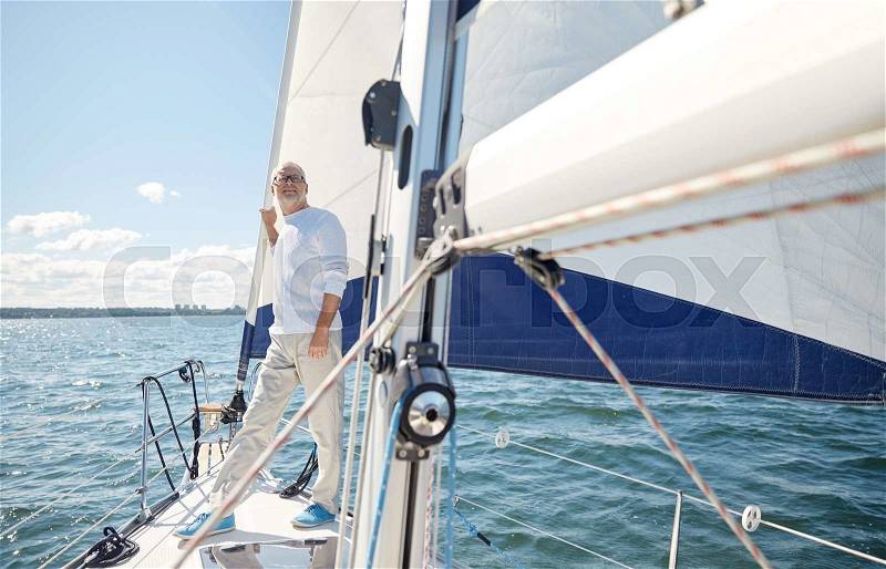 Sailing, age, tourism, travel and people concept - happy senior man on sail boat or yacht floating in sea, stock photo