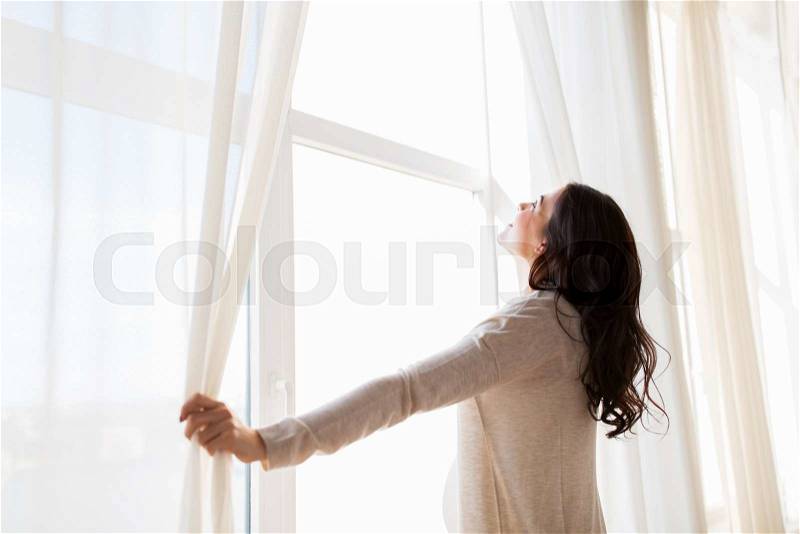 Pregnancy, motherhood, people and expectation concept - close up of happy pregnant woman opening window curtains, stock photo