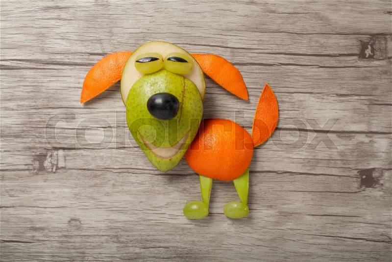 Funny dog made of fresh fruits on board, stock photo