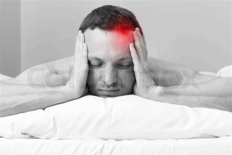 Portrait of Young man in bed with headache. Black and white stylized photo with red local ache spot, stock photo