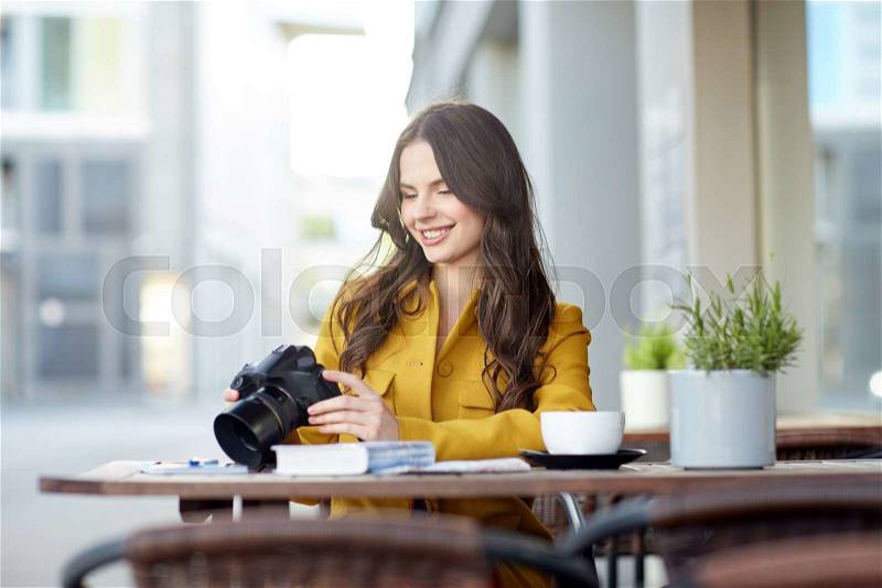 Travel, tourism, photography, leisure and people concept - happy young tourist woman or teenage girl with digital camera photographing and drinking cocoa at city street cafe terrace, stock photo