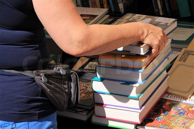 The lady buys the stack of books at the yearly book market in the city Deventer in the summer, stock photo