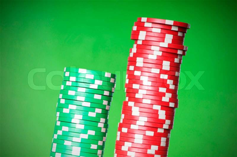 Stack of red and green casino chips against green background, stock photo