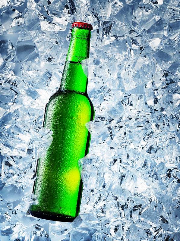 Green bottle of beer with drops on ice cubes, stock photo