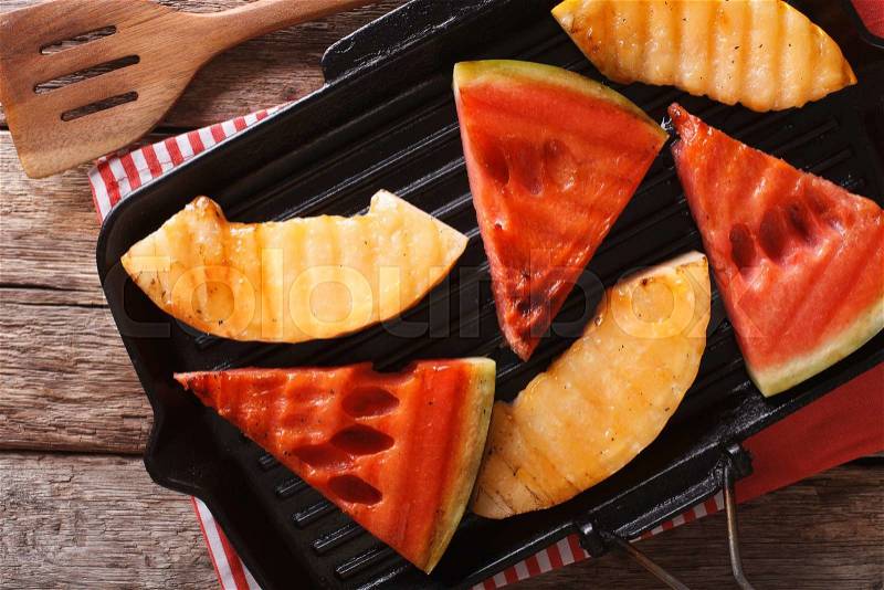 Slices of ripe watermelon and melon in a pan grill close-up on the table. Horizontal view from above , stock photo