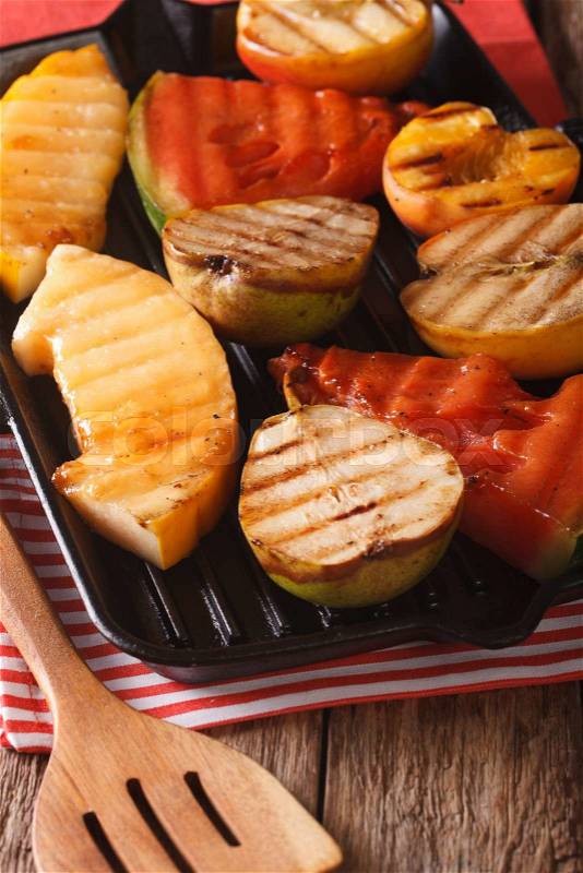 Roasted apple, melon, pear, watermelon and peach on a grill pan closeup. vertical\, stock photo