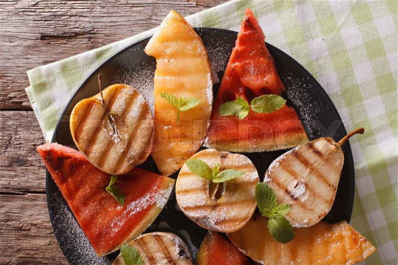 Healthy fruits grilled with mint close up on a plate on the table. horizontal view from above , stock photo