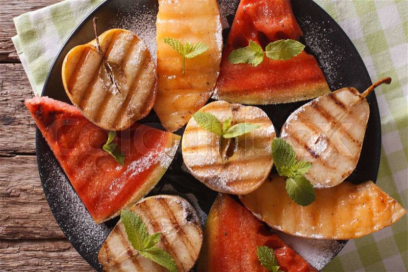 Grilled fruit: watermelon, melon, apple, pear on a plate macro. Horizontal view from above , stock photo