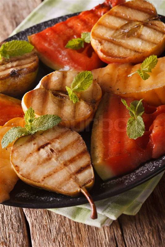 Healthy fruits grilled with mint close up on a plate on the table. vertical\, stock photo
