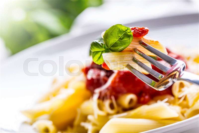 Pasta Penne with Tomato Bolognese Sauce, Parmesan Cheese and Basil on a Fork. Mediterranean food.Italian cuisine, stock photo