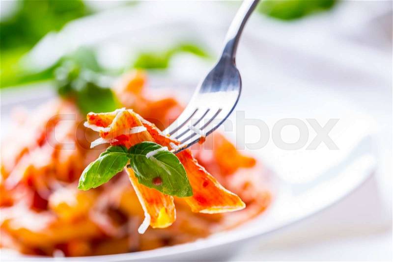 Pasta Penne with Tomato Bolognese Sauce, Parmesan Cheese and Basil on a Fork. Mediterranean food.Italian cuisine, stock photo