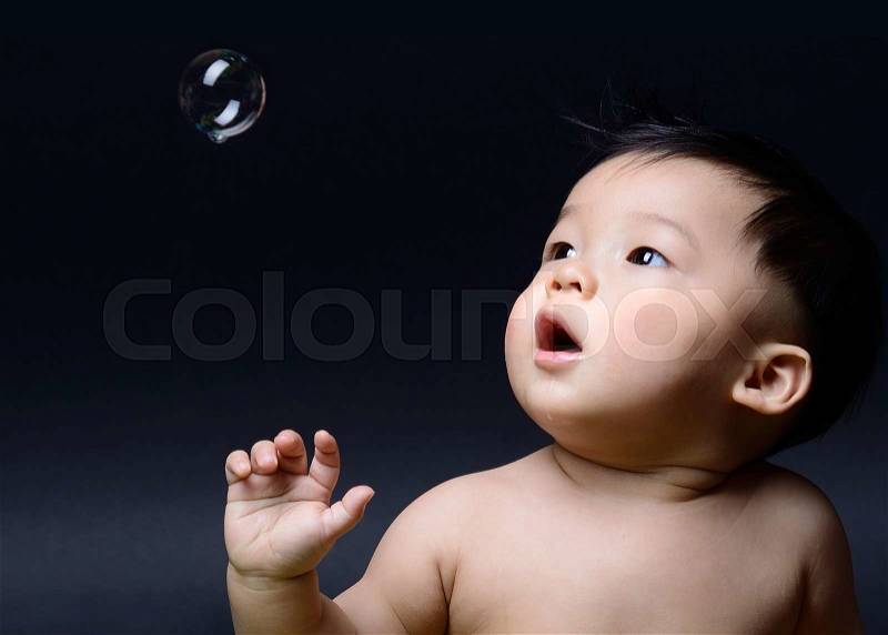 Little baby asian boy drooling and looking to soap bubble, stock photo