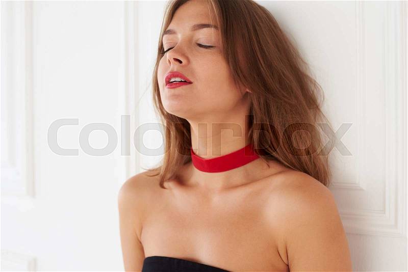 A gorgeous women is taking a deep breath with closed eyes. Her hair falls in soft layers around bare shoulders, stock photo