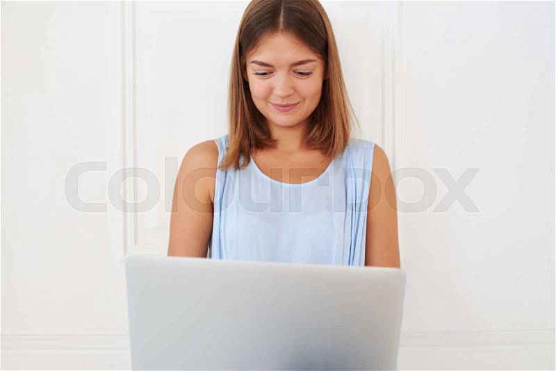 Peace of mind of young delighted girl while using her laptop, sitting on the floor isolated against a white background, stock photo
