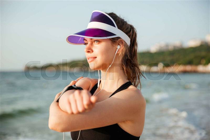 Female young fitness runner doing warm-up routine on beach before running, stock photo