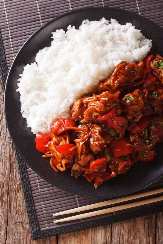 Rice with stewed pork in sweet and sour sauce on the plate closeup. vertical view from above\, stock photo