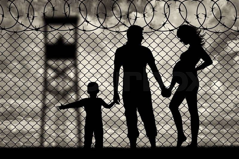Refugees concept. Young refugee family with a child near the fence of barbed wire, stock photo