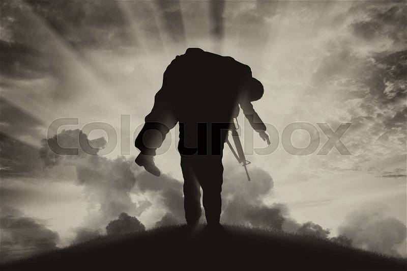 War and conflict concept. Soldier carries a wounded soldier on a background of the sky in smoke, stock photo