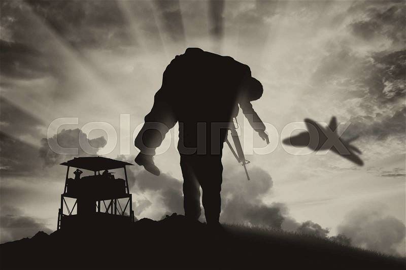 War and conflict concept. Soldier carries a wounded soldier on a background of a watchtower and flying fighter, stock photo