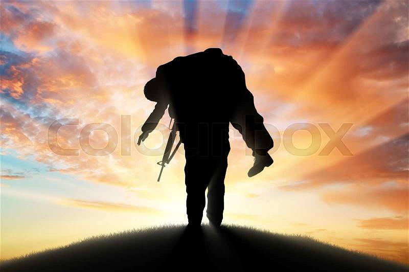 War and conflict concept. Soldier carries a wounded soldier at sunset, stock photo