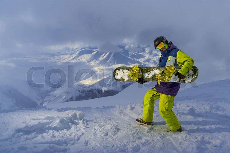 Funny snowboarder plays on the board in the mountains in winter, stock photo