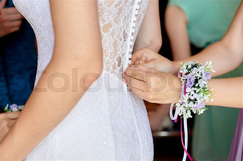 Bridesmaid is helping the bride to dress, stock photo