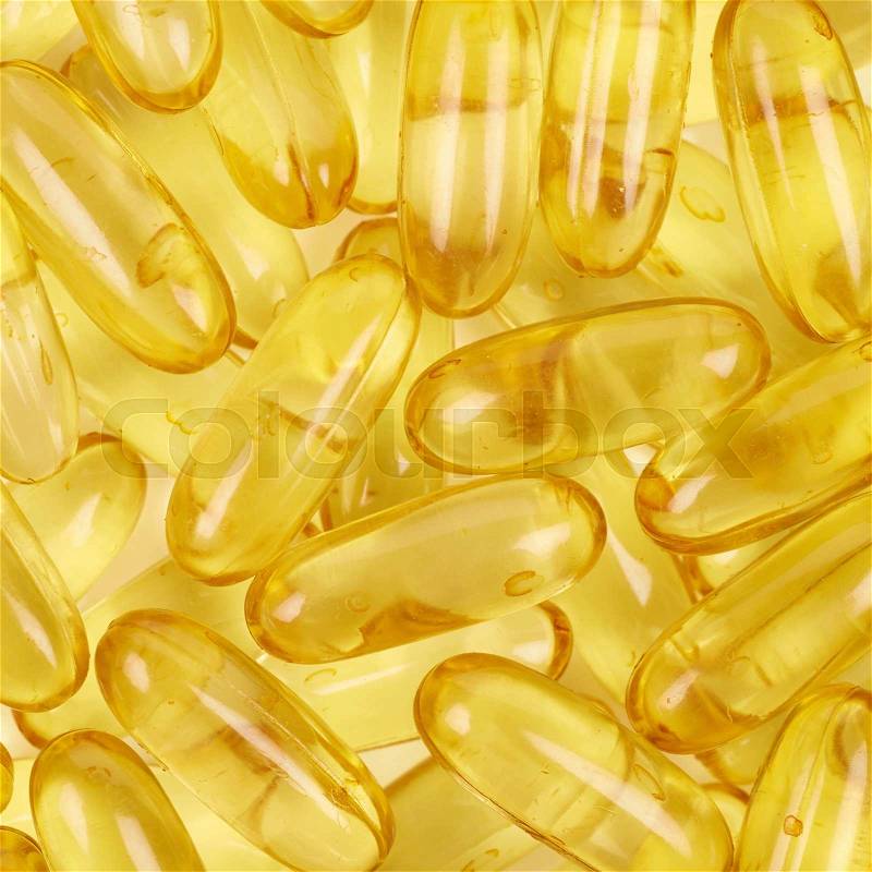 Surface covered with multiple yellow softgel pills as a medical backdrop composition, stock photo