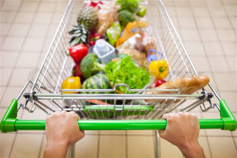 Man with trolley full of products in supermarket top view, stock photo