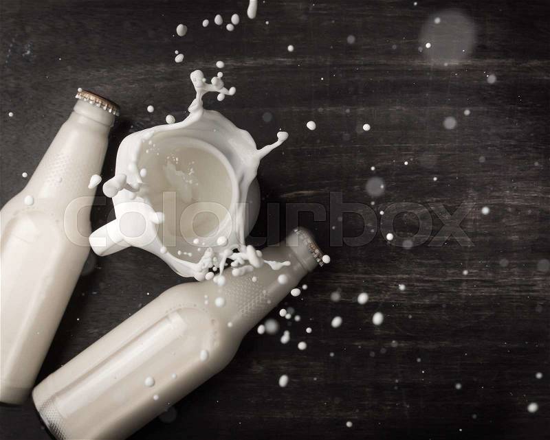 Milk splash and bottle milk on dark wooden table,Top view , stock photo