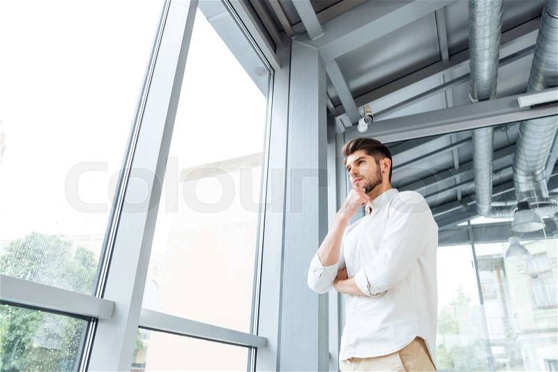 Pensive attrative young man thinking and looking at the window, stock photo