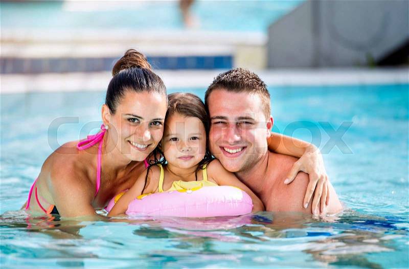 Young mother and father with their daughter in inflatable ring in swimming pool in aqua park. Summer heat and water, stock photo
