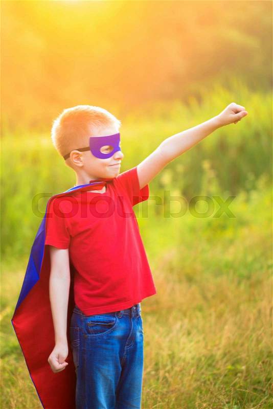 Child playing and portraying super hero and super man outdoors, stock photo