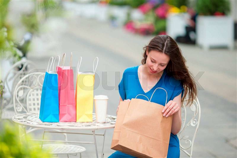 Fashion happy girl with bags after shopping drinking coffee in openair cafe. Sale, consumerism and people concept. Caucasian girl enjoy warm day in outdoor cafe, stock photo