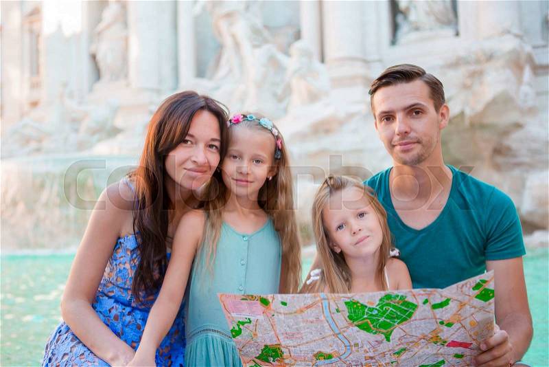 Portrait of family with touristic map near Fontana di Trevi, Rome, Italy. Happy parents and kids enjoy italian vacation holiday in Europe, stock photo